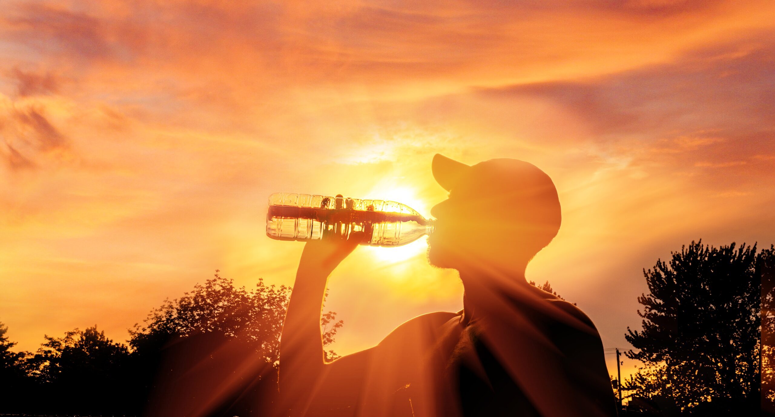 Silhouette of a worker drinking water during a heat wave